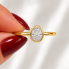 Close-up of an oval-cut lab-grown diamond bezel-set solitaire engagement ring in yellow gold