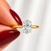 Close-up of an oval-cut lab-grown diamond cathedral solitaire engagement ring in yellow gold