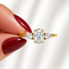 Close-up of an oval-cut lab-grown diamond trilogy engagement ring in yellow gold