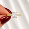 Close-up of an oval-cut lab-grown diamond pavé solitaire engagement ring in yellow gold
