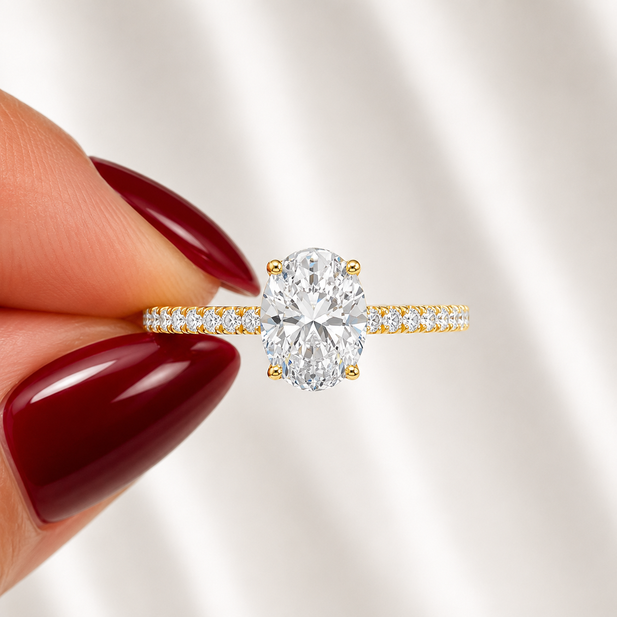 Close-up of an oval-cut lab-grown diamond pavé solitaire engagement ring in yellow gold