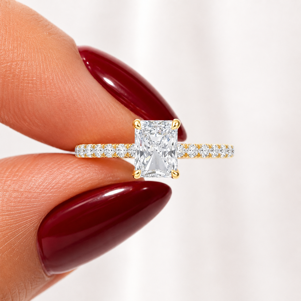 Close-up of a radiant-cut lab-grown diamond hidden halo pavé engagement ring in yellow gold